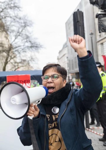 Image of Vandana Aparanti speaking into loudspeaker.